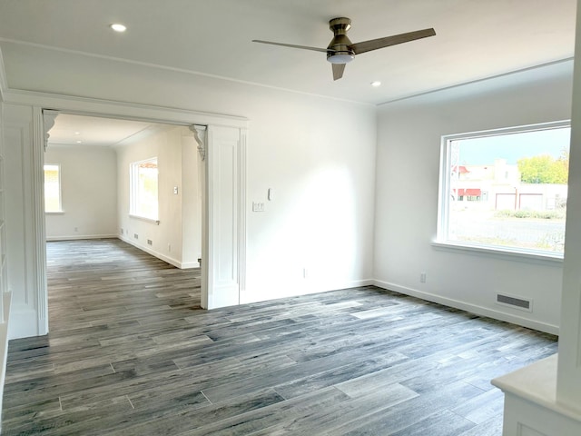 unfurnished room featuring ceiling fan, dark wood-type flooring, and a healthy amount of sunlight