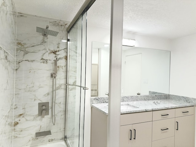 bathroom featuring vanity, an enclosed shower, and a textured ceiling