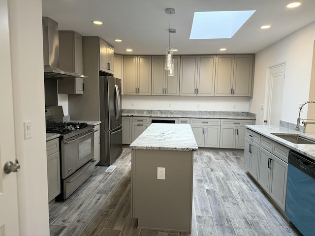 kitchen featuring wall chimney exhaust hood, sink, gray cabinetry, a center island, and stainless steel appliances