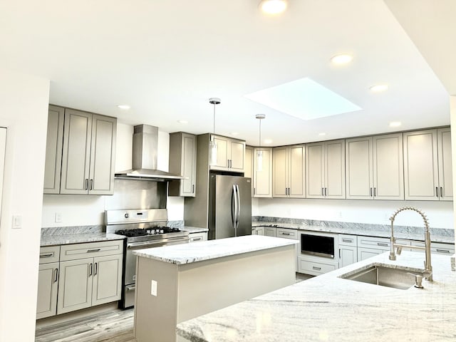 kitchen with wall chimney exhaust hood, sink, pendant lighting, stainless steel appliances, and light stone countertops