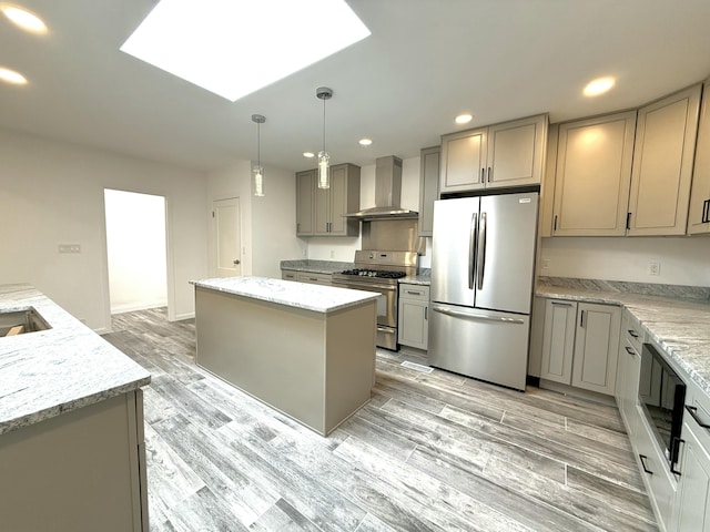 kitchen featuring wall chimney exhaust hood, gray cabinetry, light stone counters, a center island, and stainless steel appliances