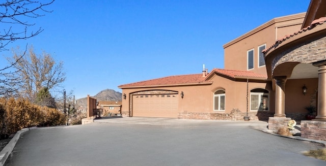 view of front facade with stucco siding, a mountain view, a garage, driveway, and a tiled roof