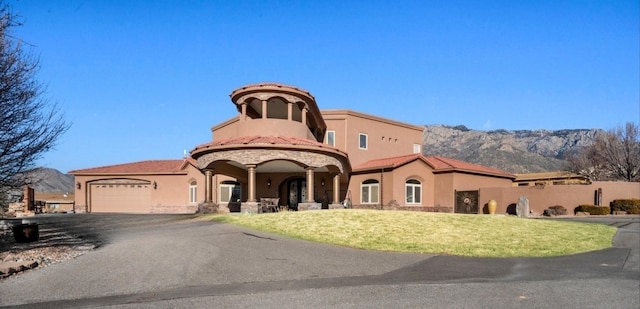 view of front of property with aphalt driveway, a tiled roof, an attached garage, a front yard, and stucco siding