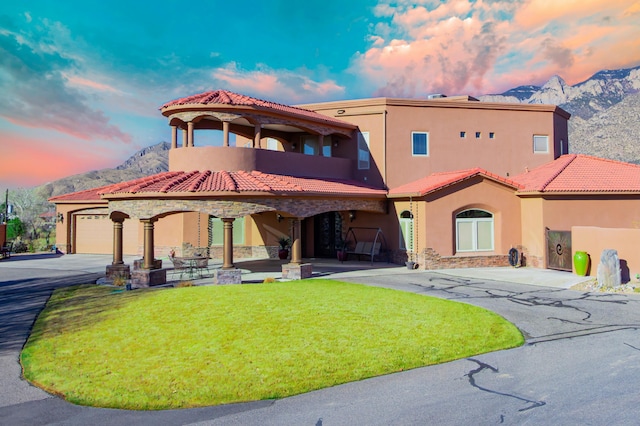 view of front of property with stucco siding, a front yard, a mountain view, and a tiled roof