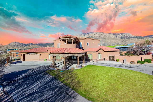 mediterranean / spanish-style home with driveway, a mountain view, a lawn, and a tiled roof