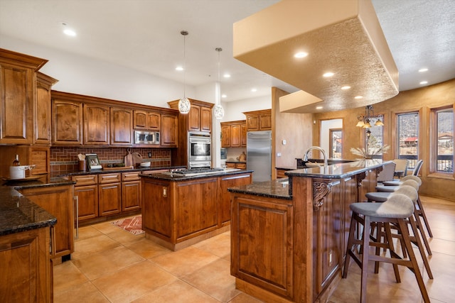 kitchen with stainless steel appliances, brown cabinets, a large island with sink, and decorative backsplash