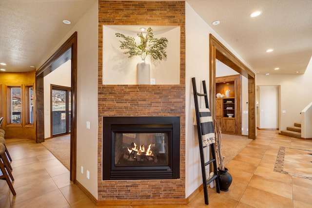 living area featuring stairway, tile patterned flooring, a textured ceiling, a multi sided fireplace, and recessed lighting