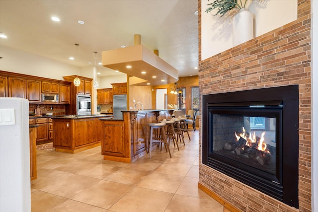 kitchen with appliances with stainless steel finishes, a center island, brown cabinets, and a breakfast bar