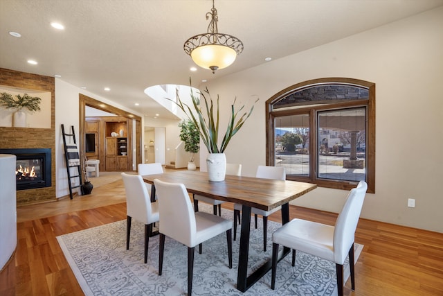 dining area featuring recessed lighting, a textured ceiling, wood finished floors, and a glass covered fireplace