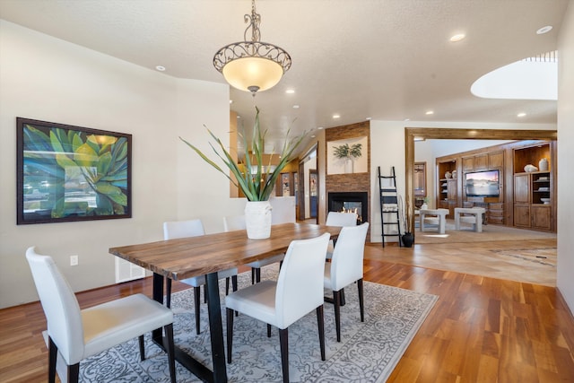 dining area featuring recessed lighting, a large fireplace, vaulted ceiling, a textured ceiling, and wood finished floors