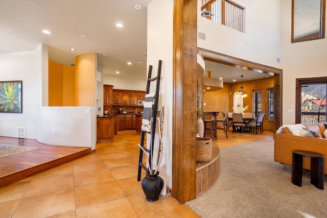 interior space featuring light tile patterned flooring, a towering ceiling, visible vents, and recessed lighting