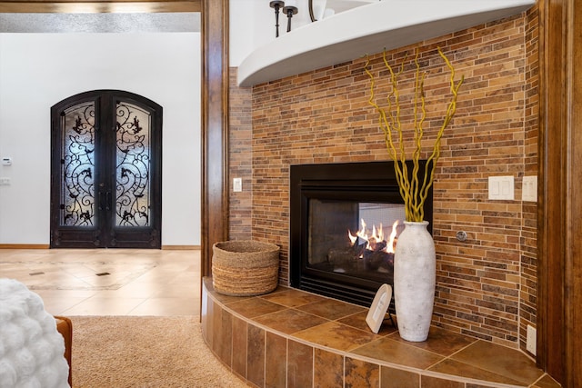 details with arched walkways, french doors, a tiled fireplace, and baseboards