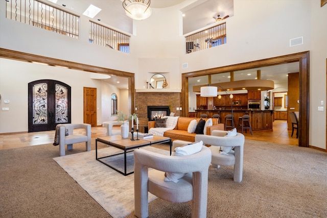 living area featuring light carpet, visible vents, a high ceiling, french doors, and a multi sided fireplace