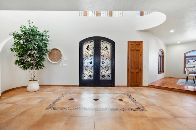 tiled foyer entrance with arched walkways, french doors, recessed lighting, and baseboards