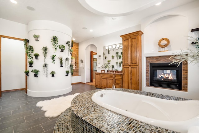 full bath with recessed lighting, baseboards, a bath, and vanity