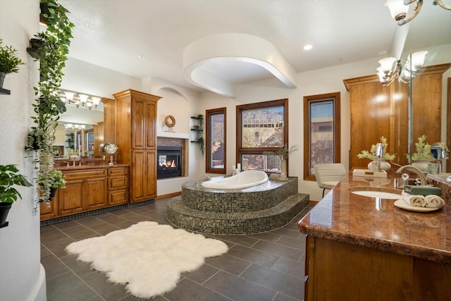 full bath with two vanities, a sink, a multi sided fireplace, and a bath