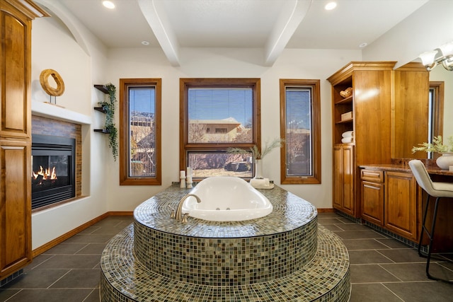 full bath featuring recessed lighting, a glass covered fireplace, tile patterned flooring, beamed ceiling, and a tub with jets