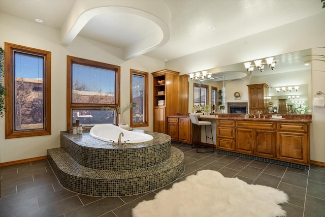 bathroom with double vanity, a sink, tile patterned flooring, baseboards, and a bath