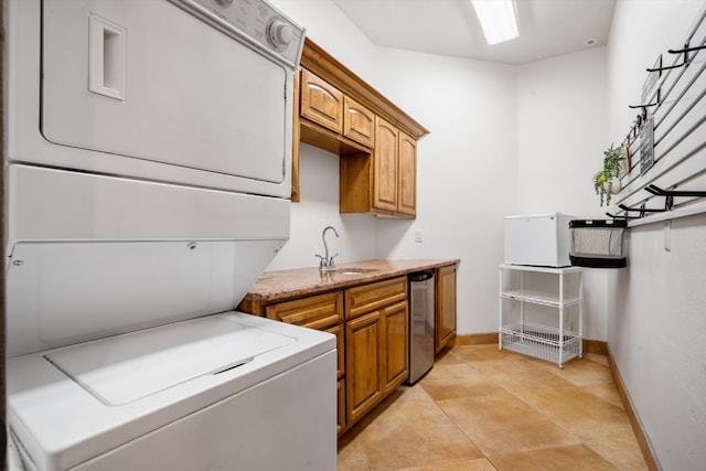 laundry room featuring light tile patterned flooring, baseboards, a sink, and stacked washer and clothes dryer