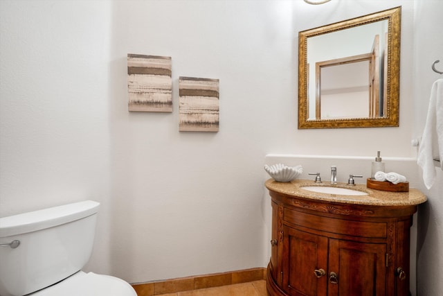 bathroom with tile patterned flooring, baseboards, vanity, and toilet