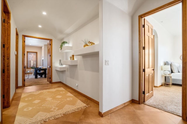 hallway featuring baseboards, arched walkways, vaulted ceiling, and recessed lighting