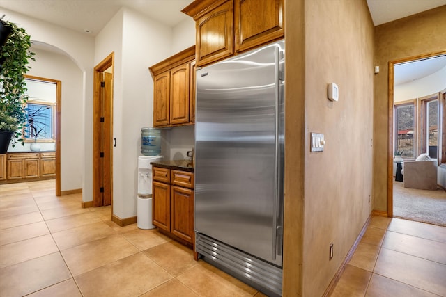 kitchen featuring built in fridge, brown cabinets, and light tile patterned flooring