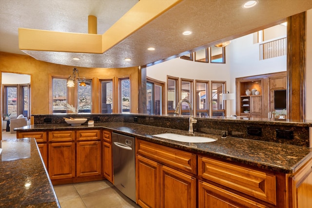 kitchen with light tile patterned floors, recessed lighting, a sink, brown cabinetry, and dark stone countertops