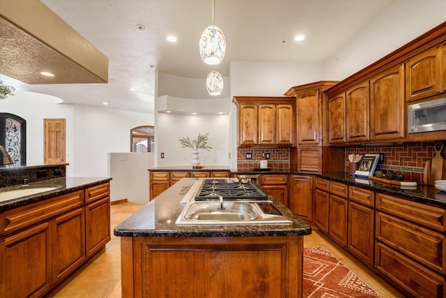 kitchen with stainless steel appliances, a kitchen island, backsplash, and a sink