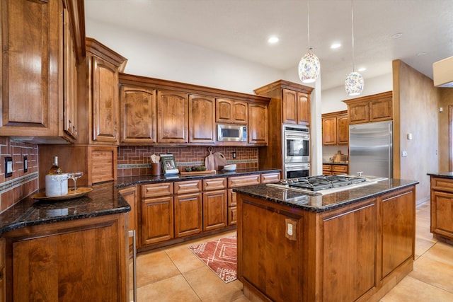 kitchen with light tile patterned floors, a kitchen island, appliances with stainless steel finishes, brown cabinets, and tasteful backsplash