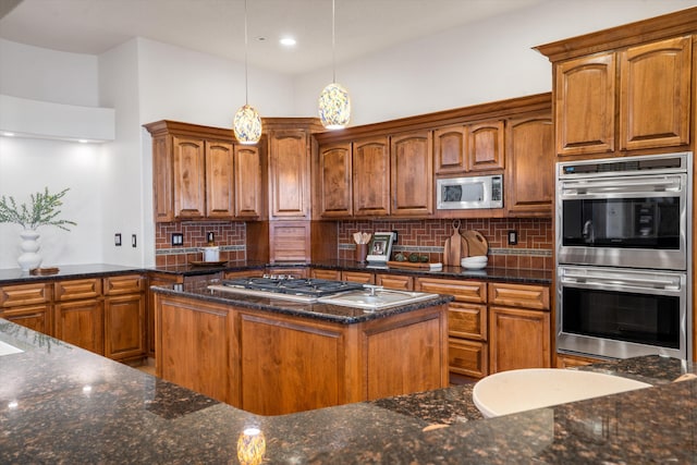 kitchen with stainless steel appliances, hanging light fixtures, dark stone countertops, and decorative backsplash