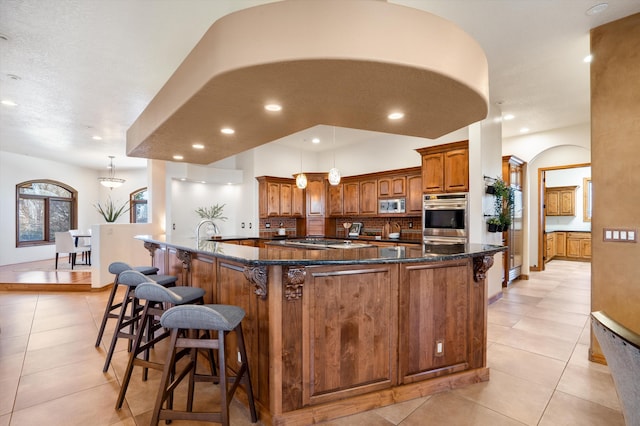 kitchen featuring appliances with stainless steel finishes, a breakfast bar, a large island with sink, and tasteful backsplash