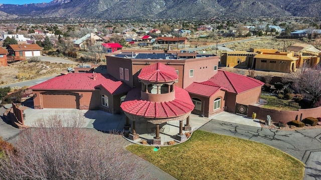 view of front facade featuring an attached garage, a mountain view, driveway, a tiled roof, and stucco siding