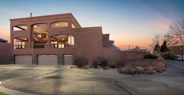 view of front of property with a garage, driveway, a balcony, and stucco siding