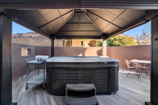 wooden deck featuring outdoor dining space, fence, a hot tub, and a gazebo