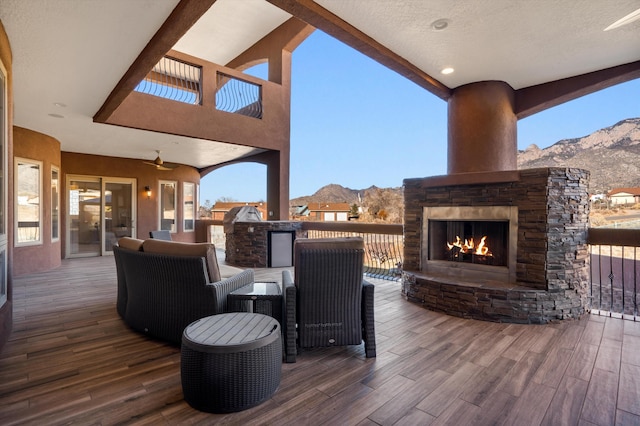 wooden terrace with an outdoor stone fireplace and a mountain view