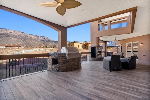 view of patio featuring exterior kitchen, ceiling fan, a deck with mountain view, and area for grilling