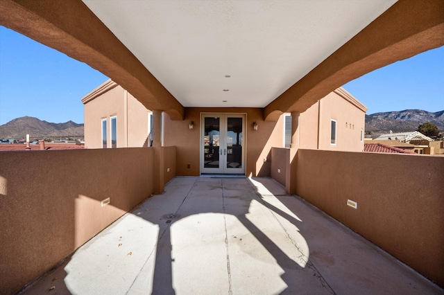 view of patio / terrace featuring french doors, a balcony, and a mountain view