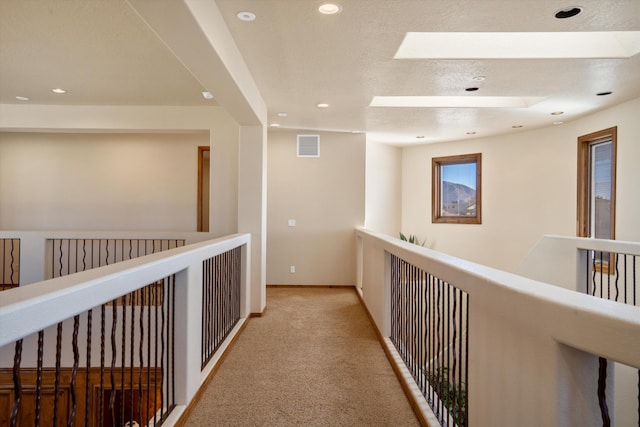 corridor featuring recessed lighting, a skylight, carpet flooring, visible vents, and baseboards