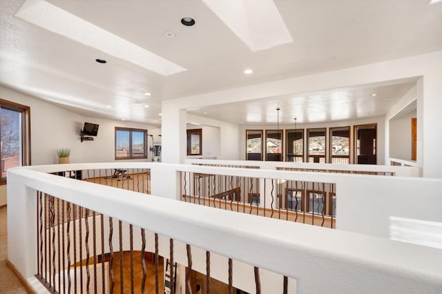 hall with a skylight, an upstairs landing, and recessed lighting