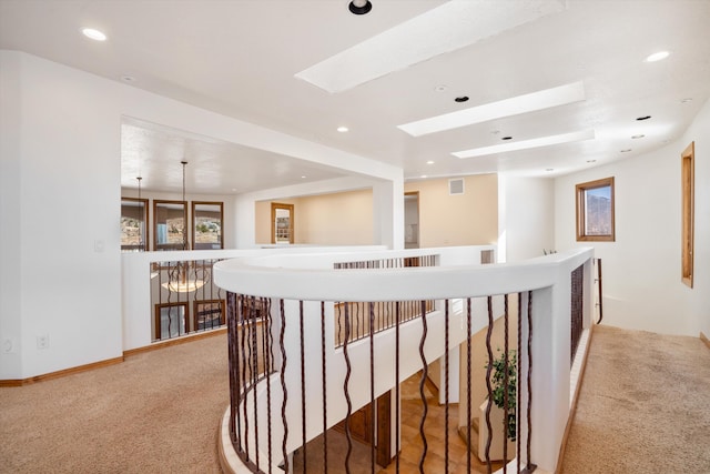 hallway with light carpet, a skylight, an upstairs landing, and recessed lighting