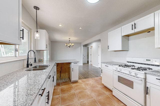 kitchen with gas range gas stove, sink, white cabinetry, and pendant lighting