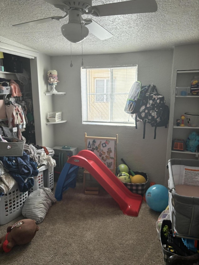 rec room featuring carpet, ceiling fan, and a textured ceiling