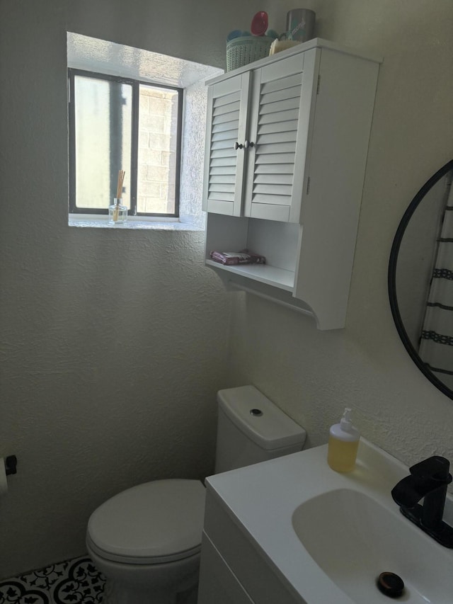 bathroom featuring a textured wall, vanity, and toilet