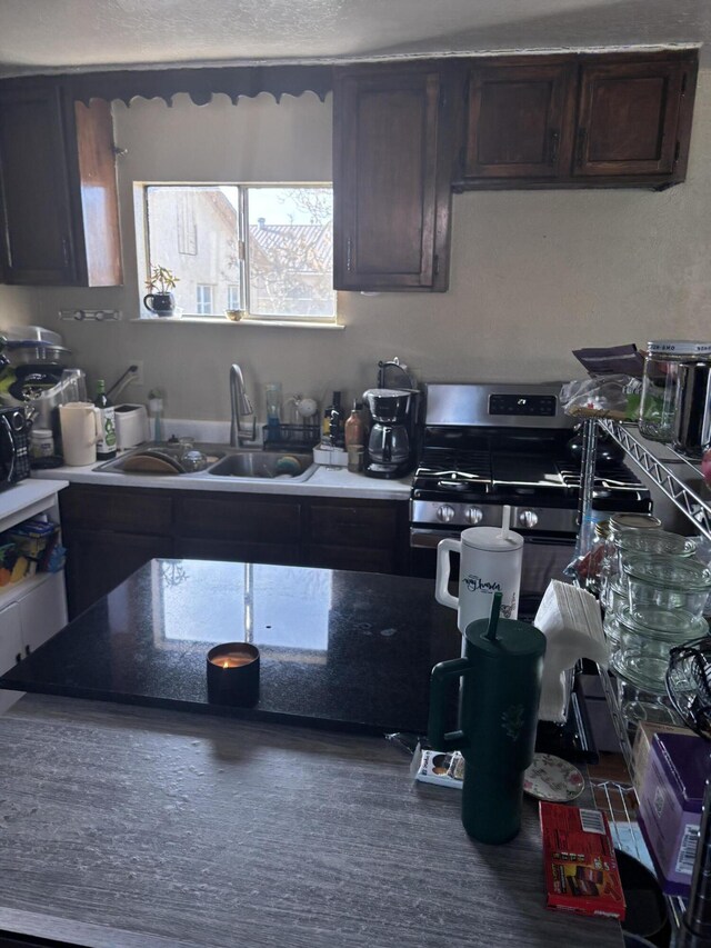 kitchen with sink, dark brown cabinets, and stainless steel range with gas cooktop