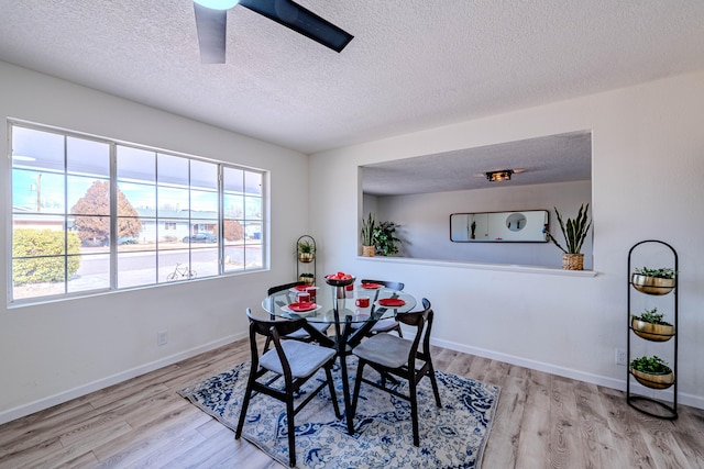 dining room with a ceiling fan, a textured ceiling, baseboards, and wood finished floors