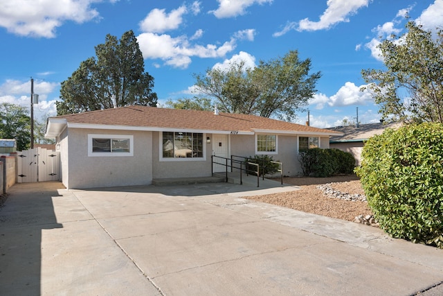 ranch-style home featuring a shingled roof, a gate, fence, and stucco siding