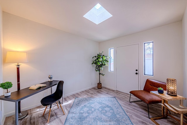 office featuring a skylight, light wood-style flooring, and baseboards