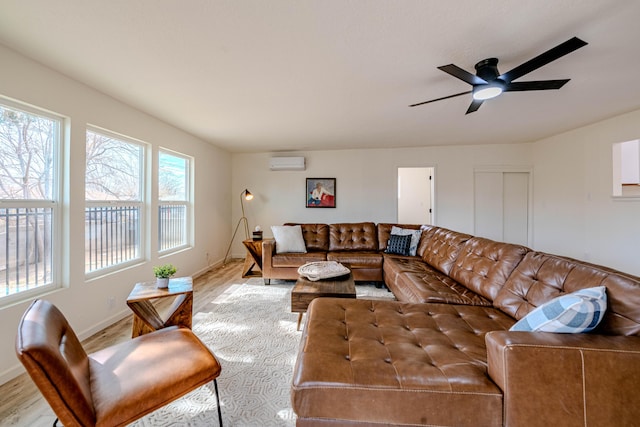 living area with a ceiling fan, a wall mounted air conditioner, baseboards, and wood finished floors