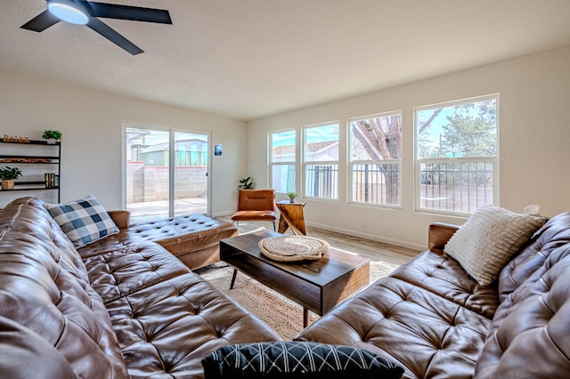 living room with plenty of natural light, wood finished floors, a ceiling fan, and baseboards