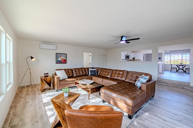 living area with an AC wall unit, light wood finished floors, and a ceiling fan